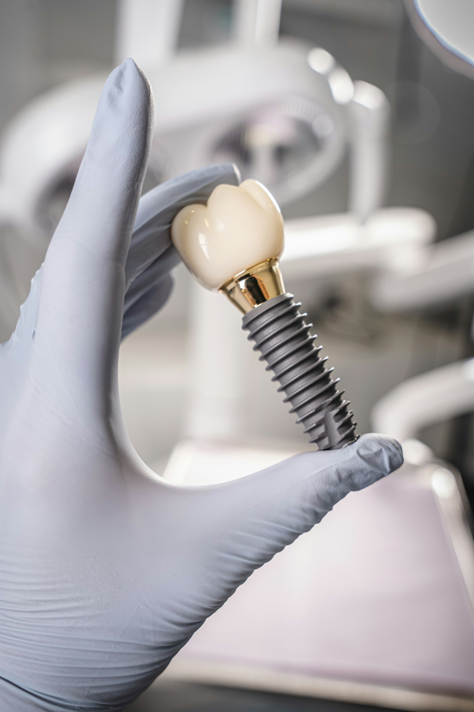 Implantaat met zirkoniumkroon en goudkleurig abutment, vastgehouden met handschoen